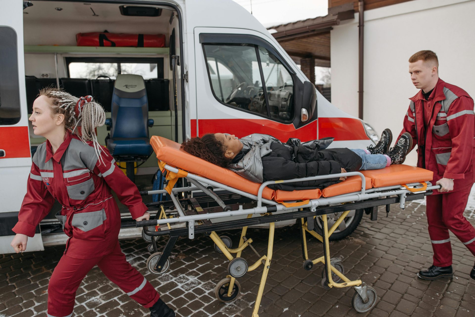 Rettungssanitäter helfen einem Patienten auf einer Trage in einen Rettungswagen und veranschaulichen dabei den Notfalleinsatz.